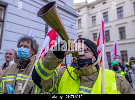 Schwerin, Deutschland. 23rd. November 2021. Ein Feuerwehrmann bläst während des zentralen Warnstreiks vor dem Finanzministerium einen Schlag. Rund 400 Lehrer, Universitätsangestellte, Polizisten oder Feuerwehrleute nehmen an dem zentralen Warnstreik Teil. Die Aktion soll den Druck auf die Arbeitgeber bei den Tarifverhandlungen des öffentlichen Dienstes erhöhen. Quelle: Jens Büttner/dpa-Zentralbild/dpa/Alamy Live News Stockfoto