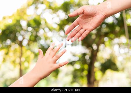 Vater hält die Hand des Sohnes in einem öffentlichen Garten Stockfoto