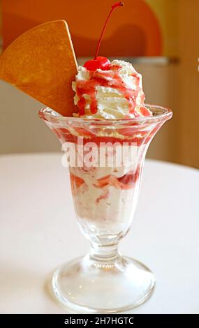 Köstliche Erdbeer-Eisbecher, serviert auf dem weißen Tisch Stockfoto