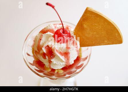 Nahaufnahme der Maraschino-Kirsche mit Erdbeer-Eiscreme und Sundae-Schlagsahne Stockfoto