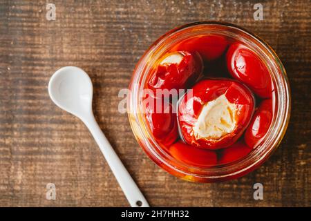 Gefüllte Kirschpaprika mit Ricotta-Käsefüllung im Glas auf Holzboden Stockfoto