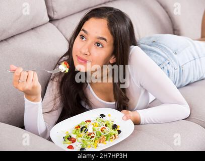 Positive junge Frau, die Salat isst Stockfoto