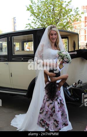 Ein atemberaubendes multikulturelles Bild, das eine weiße kaukasische Braut und ihr schwarzes farbenes Blumenmädchen an ihrem Hochzeitstag zeigt. Stockfoto