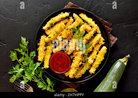 Gebackene Zucchini-Sticks auf dem Teller. Draufsicht, flach liegend Stockfoto
