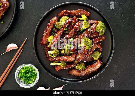 Rindfleisch und Brokkoli unter Rühren auf dunklem Grund braten. Draufsicht, flach liegend Stockfoto