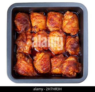 Gebratene Hähnchenschenkel auf Backblech isoliert auf weißem Hintergrund. Gekochte gebackene Hühnerteile liegen auf einem Holztisch. Nahaufnahme, Draufsicht Stockfoto