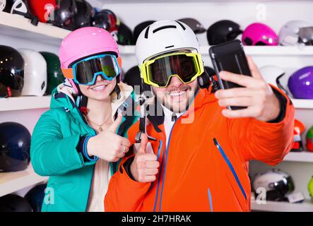 Glückliches Paar in Skiausrüstung, das Selfie beim Einkaufen macht Stockfoto