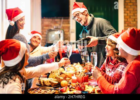 Millennial Freunde auf weihnachtsmützen Weihnachten mit Champagner und Süßigkeiten Essen in Blockhütte - Winterurlaub Konzept mit jungen Menschen Stockfoto