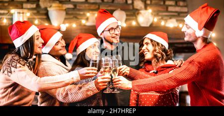Junge Freunde mit weihnachtsmützen feiern Weihnachten mit Champagner Wein Toast zu Hause Wiedervereinigung - Winterurlaub Konzept mit glücklichen Millennials Stockfoto