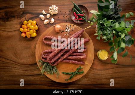 polnische Rinderkabanos-Würstchen auf rustikalem Holztisch mit natürlichen Zutaten Stockfoto