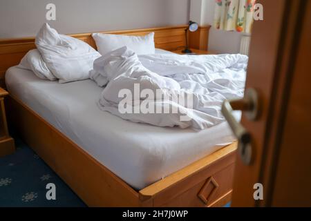 Oberwiesenthal, Deutschland. 23rd. November 2021. Ein Blick in ein Zimmer mit einem verlassenen ungefertigten Bett. Hotelgäste mussten aufgrund der neuen Corona-Landesverordnung ihr Doppelzimmer in einem Hotel verlassen. Seit Montag (22,11.) gilt in Sachsen eine teilweise Sperrung für große Teile des öffentlichen Lebens. Hotels dürfen nur für Geschäftsreisende geöffnet werden. Quelle: Jan Woitas/dpa-Zentralbild/dpa/Alamy Live News Stockfoto