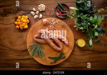 polnisch geräucherte Kielbasa-Würstchen auf rustikalem Holztisch mit natürlichen Zutaten Stockfoto