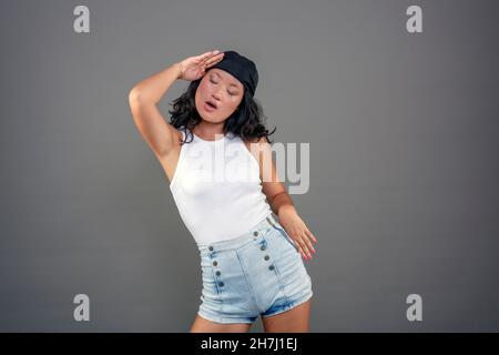 Junge chinesische Mädchen mit Bandana auf neutralem Hintergrund, setzen lustige Ausdruck. Stockfoto