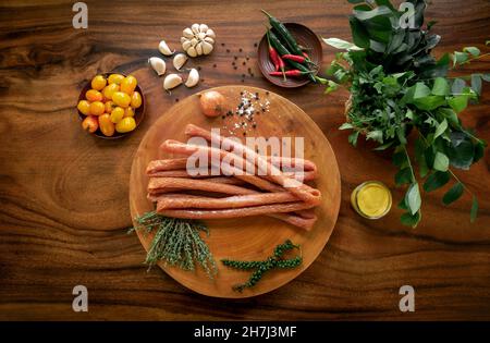 polnische Hähnchen-Kabanos-Würstchen auf rustikalem Holztisch mit natürlichen Zutaten Stockfoto