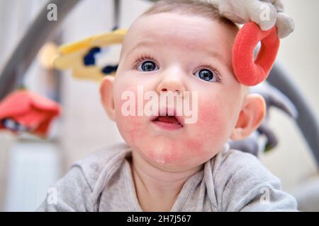 Kleinkind spielt auf einer Matte liegend, über der Spielzeug hängt Stockfoto