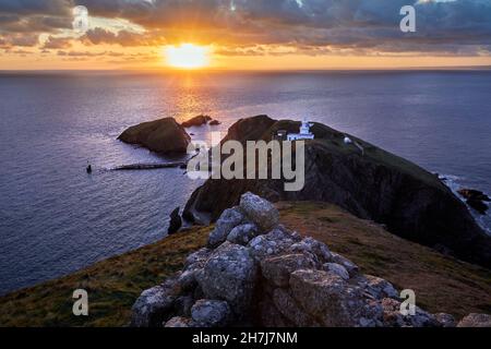 Sonnenaufgang über Süden Licht Leuchtturm und die oldenberg Landung Jetty aus Mariscos" Schloss auf der Insel Lundy vor der Küste von Devon, Großbritannien Stockfoto