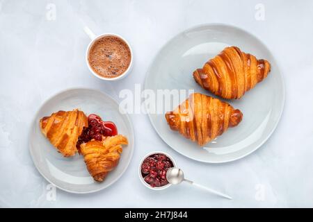 Croissants und Marmelade. Zwei graue Teller auf einem Marmortisch. Draufsicht, flach liegend. Eine Tasse Kakao am Morgen zum Frühstück. Traditionelle französische Küche. Fotolia Stockfoto