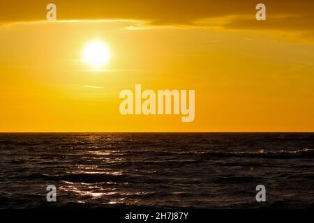 Dunkles Wasser der Ostsee. Es gibt auch die untergehende Sonne, deshalb wurde der Himmel in Sonnenuntergangsfarben gemalt, was man an der Küste in Kolobrzeg sieht Stockfoto