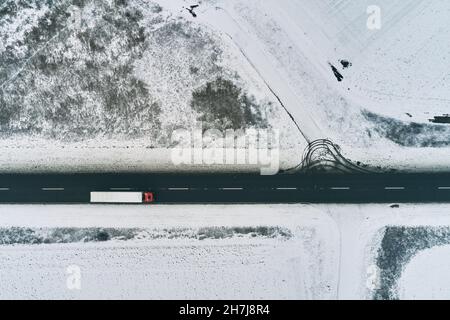 Luftaufnahme eines Sattelschleppers, der im Winter die Straße entlang durch die Landschaft fährt, Drone pov Stockfoto