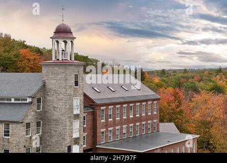 Schöner Himmel und farbenfrohe Herbstszene in der historischen Stadt Harrisville, New Hampshire. Alter Glockenturm und erhaltene Textilmühlengebäude. Stockfoto