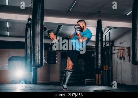 Junge Muskel Boxer mit einem Boxsack in der Turnhalle. Boxer schlagen Stanzgeschwindigkeit Tasche Stockfoto