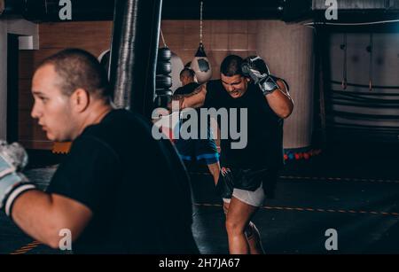 Junge Muskel Boxer mit einem Boxsack in der Turnhalle. Boxer schlagen Stanzgeschwindigkeit Tasche Stockfoto