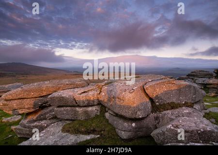 Dartmoor, Devon, Großbritannien. 23. November 2021. Wetter in Großbritannien: Ein spektakulärer Sonnenuntergang über Dartmoor, während sich grüblernde Wolken über Pew Tor sammeln, während das Wetter nach einem hellen und sonnigen Tag bricht. Kredit: PQ/Alamy Live News Stockfoto