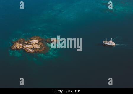 Luftbild Schiff segelt zur Insel in Meer Drohne Landschaft türkisfarbenes Wasser von oben minimalistischen Stil Stockfoto