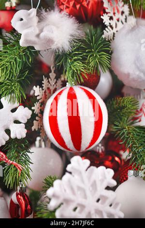 Gestreifte rot-weiße Weihnachtskugel auf geschmücktem Baum Stockfoto