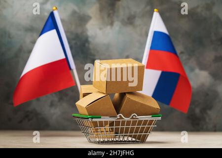 Verschiedene Kisten in einem Lebensmittelkorb und zwei Flaggen auf einem abstrakten Hintergrund, das Konzept des Handels zwischen Frankreich und Russland Stockfoto