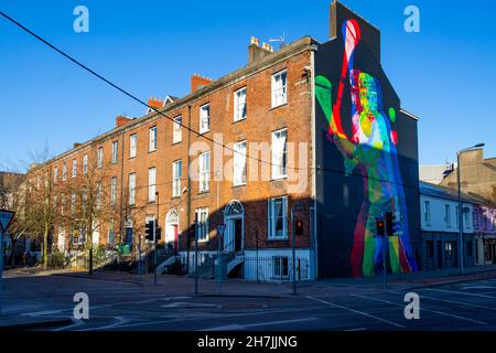 Reihe von Reihenhäusern in Cork City Ireland mit Wandbild eines Mannes, der auf einen Giebelkiebel schleudert Stockfoto