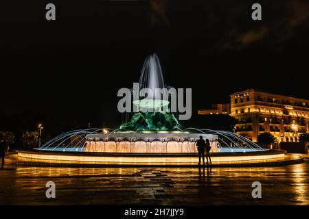 Berühmter beleuchteter Tritonbrunnen in der Nacht, drei mythologische Bronzeskulpturen mit großem Becken, modernes Wahrzeichen von Valletta. Stockfoto