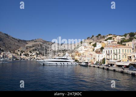 Symi Island - Griechenland - August 19 2009 : wunderschöne Hafenlandschaft mit lebhafter, farbenfroher Uferpromenade. Elegante Häuser säumen den geschäftigen Hafen. Karabinerverschluss Stockfoto