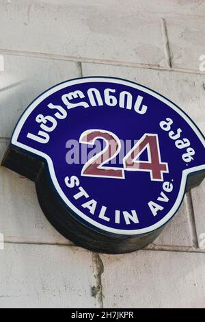 Schild mit Straßennamen in georgischer und englischer Sprache auf dem Gebäude der georgischen Stadt Gori sagen Stalin Avenue. Gori ist der Geburtsort von Stockfoto