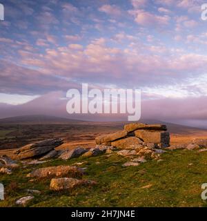 Dartmoor, Devon, Großbritannien. 23. November 2021. Wetter in Großbritannien: Ein spektakulärer Sonnenuntergang über Dartmoor, während sich grüblernde Wolken über Pew Tor sammeln, während das Wetter nach einem hellen und sonnigen Tag bricht. Kredit: PQ/Alamy Live News Stockfoto