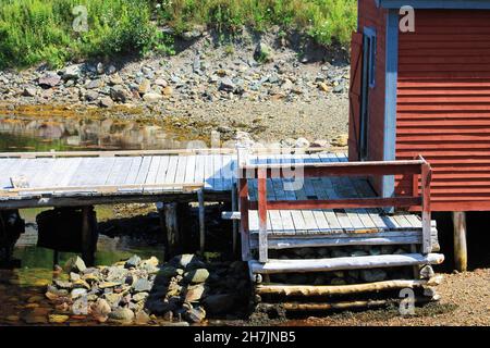 Nahaufnahme eines Fischschuppen und Pier an einem felsigen Strand. Stockfoto