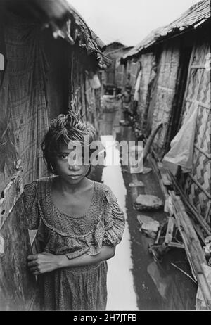 Ein junges Mädchen geht aus ihrem Slumhaus heraus, das direkt über einer Pfütze mit chemischen Abfällen aus nahegelegenen Gerbereien gebaut wurde. Jigatola, Dhaka, Bangladesch. Stockfoto