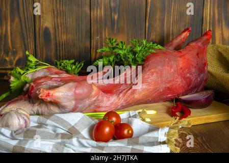 Nutria Karkasse auf einem Holzschneidebrett mit frischem Gemüse und Kräutern. Stockfoto