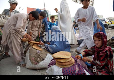 Afghanische Frauen und Kinder verkaufen gebackenes Brot auf dem Hauptmarkt von Mazar-e-Sharif in der nördlichen Provinz Balkh. Schätzungsweise 60.000 Kinder Stockfoto