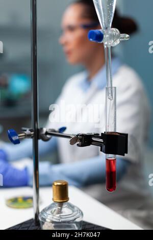 Selektiver Fokus auf Geräte der medizinischen Industrie, die auf dem Tisch stehen, transparentes Reagenzglas mit Blut darauf. Biologe Forscher, der während des Biochemie-Experiments im Labor des Biochemie-Krankenhauses arbeitet Stockfoto