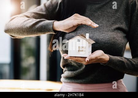 Immobilienmakler gesturing, um Häuser zu schützen, Wohnungsversicherung Konzept. Stockfoto