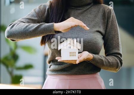 Immobilienmakler gesturing, um Häuser zu schützen, Wohnungsversicherung Konzept. Stockfoto