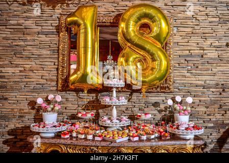 Süßigkeitenbar mit buntem Süßgebäck und Luftballons für 18 Jahre altes Mädchen im Restaurant Stockfoto