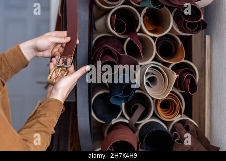 Nahaufnahme Hände von professionellen Gerber Wahl Gürtelschnalle auf Holztisch in Leder-Werkstatt Stockfoto