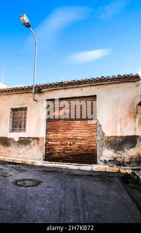 Alte bunte und beschädigte Fassade mit rostigen Blinden in Rojales, Alicante, Spanien. Stockfoto