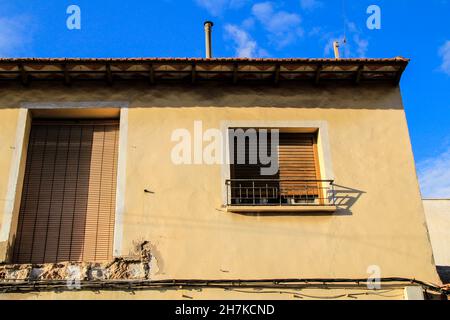 Alte Fassade mit kaputten Balkon und braunen Jalousien im Dorf Rojales, Alicante, Spanien. Stockfoto