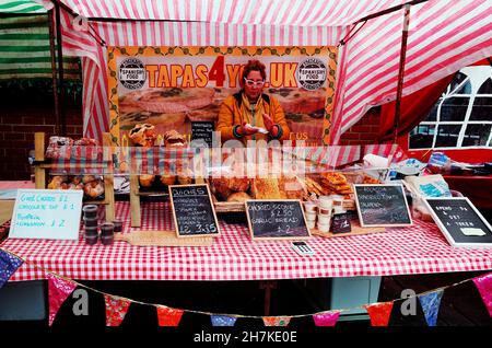 Eine Frau halter Abschaltdruck am ist ein Britischer Landwirt Markt mit einer Auswahl an spanischen Tapas essen Stockfoto