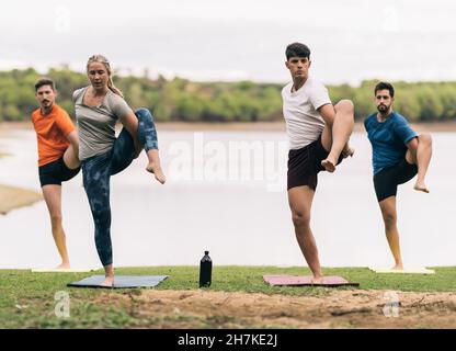 Yoga-Trainer führt einen Yoga-Kurs neben einem See in einem Park Stockfoto
