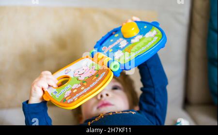 POZNAN, POLEN - 24. März 2018: Ein polnisches Fisher-Price-buntes elektronisches Buch, das von einem Baby gehalten wird Stockfoto