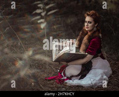 Hexe mit Buch, in Kleid vor dem Hintergrund der wilden Natur Stockfoto